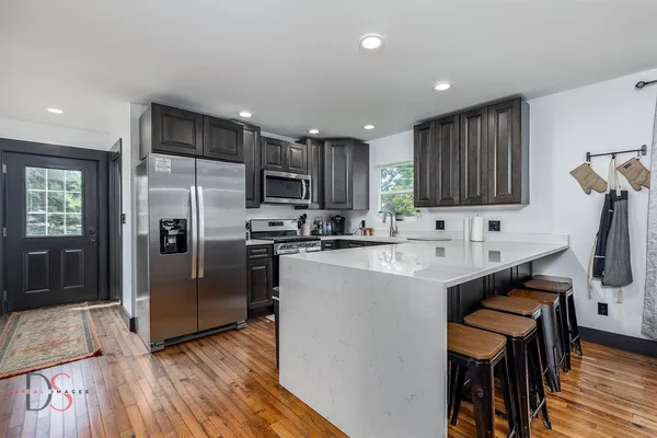a kitchen with stainless steel appliances granite countertop a refrigerator a sink a stove a microwave and wooden cabinets