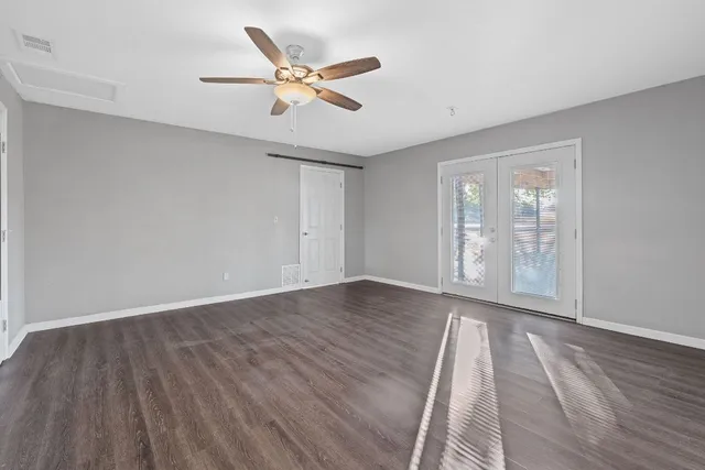 wooden floor in an empty room with a chandelier fan