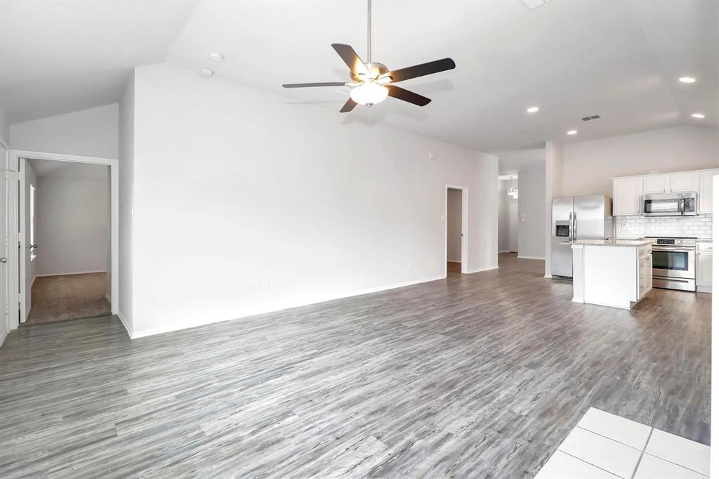 5528 Ridge View Drive Watauga, TX 76137 - Photo 9 of 16 lofted ceiling, dark wood-style floors, recessed lighting, and ceiling fan.. Fireplace.. Master bedrm. thru the door at back.. Utility room across from breakfast bar..