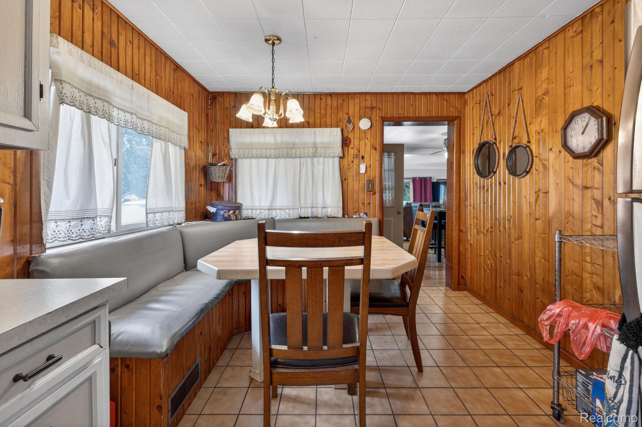 304 West Ridge Street Owosso, MI 48867 - Photo 20 of 45 Dining room with suspended lighting, light tile patterned floors, and wood walls