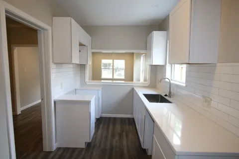 a kitchen with granite countertop white cabinets and sink