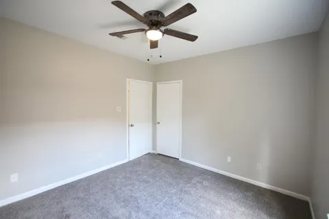an empty room with a ceiling fan and a window