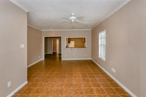 a view of an empty room with window and chandelier fan