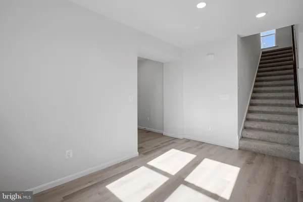 a large white kitchen with wooden floor and stainless steel appliances
