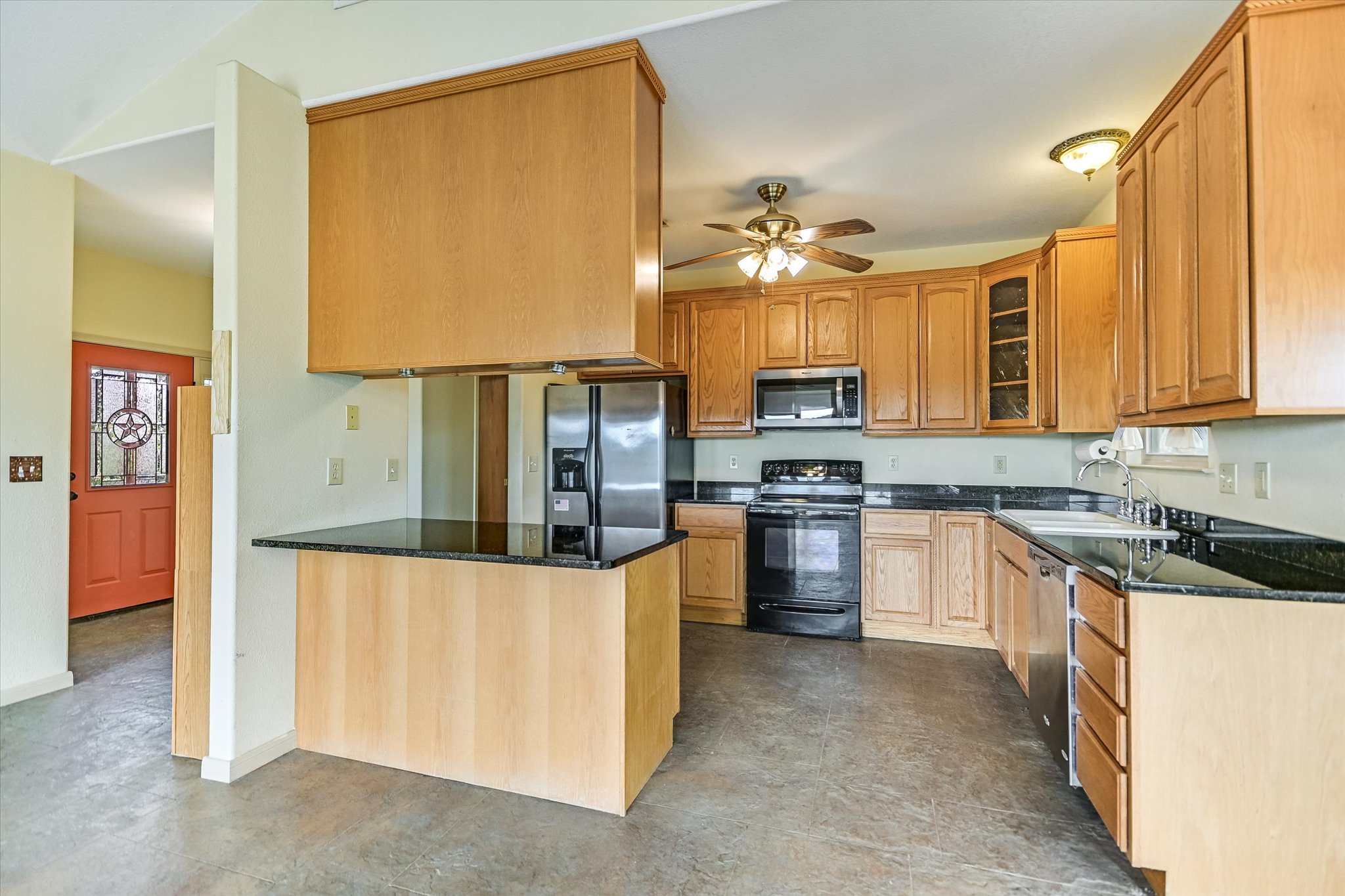 700 Cliffside Road Wimberley, TX 78676 - Photo 5 of 22 Spacious kitchen featuring extensive light wood cabinetry, dark countertops, and stainless steel appliances