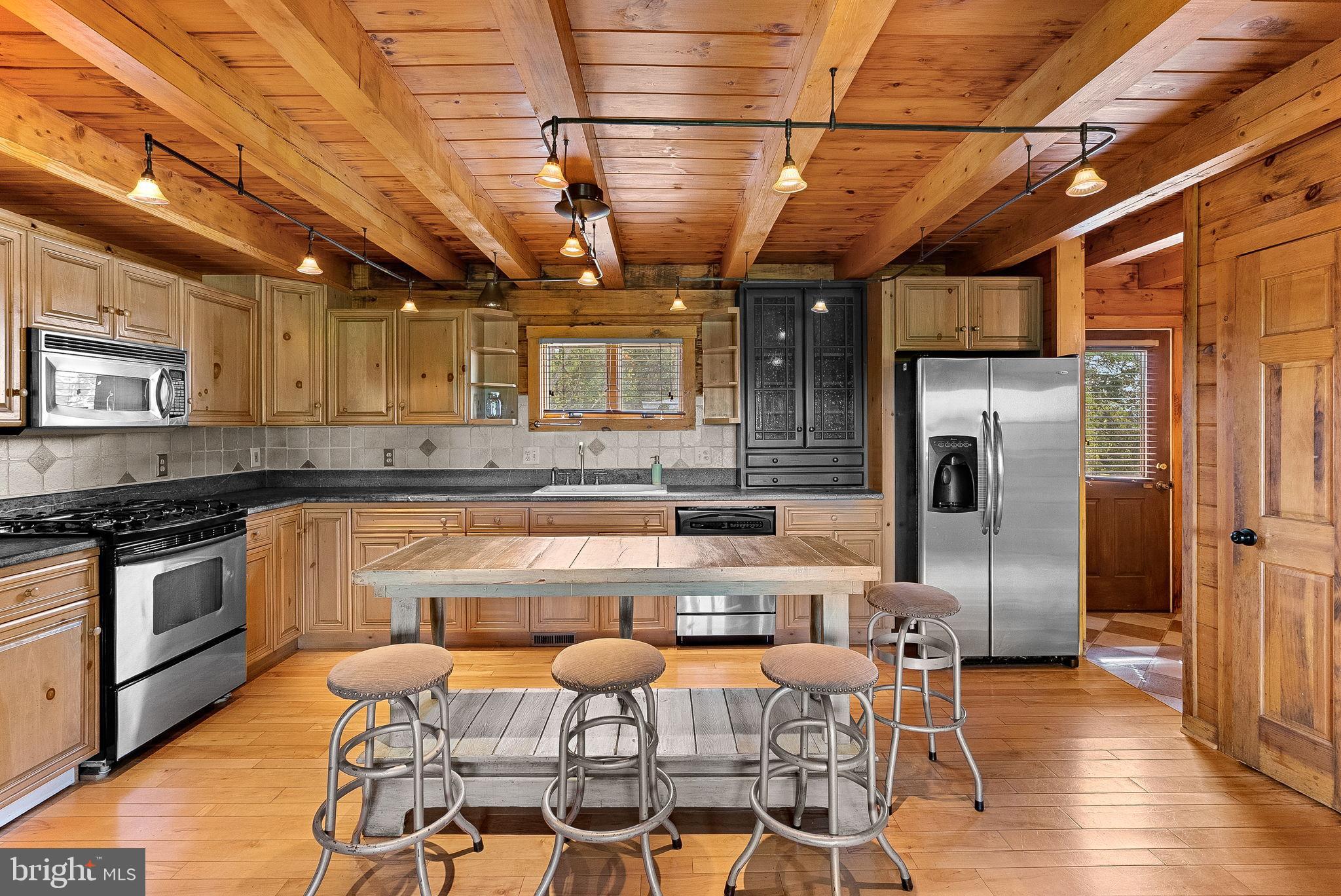 18837 Trinity Church Road Purcellville, VA 20132 - Photo 17 of 73 a kitchen with stainless steel appliances granite countertop a table chairs refrigerator and wooden cabinets