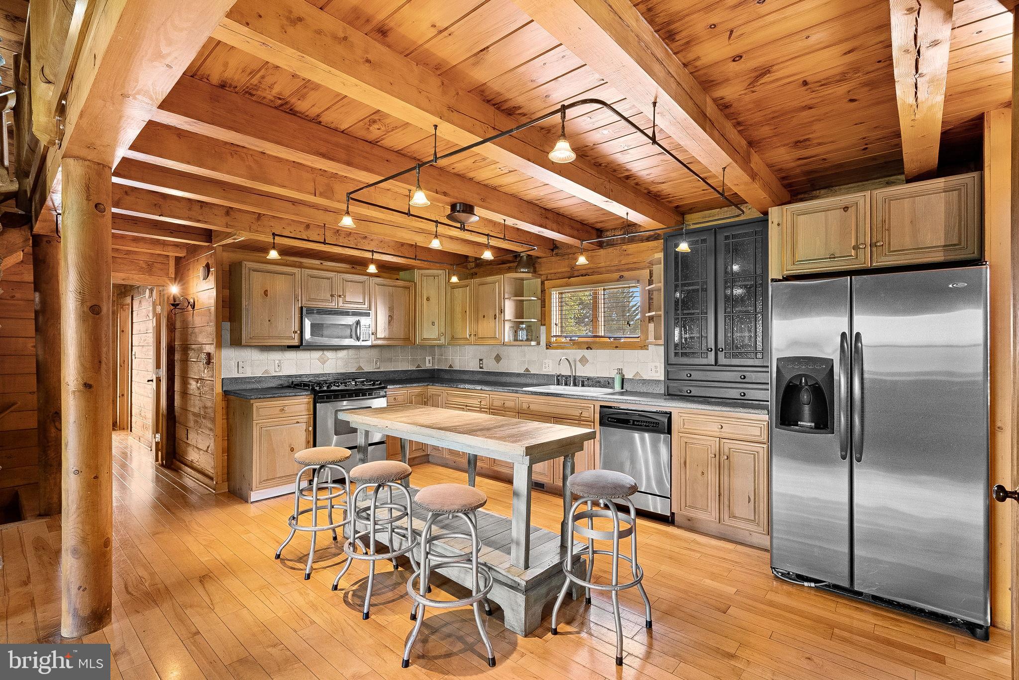 18837 Trinity Church Road Purcellville, VA 20132 - Photo 18 of 73 a kitchen with stainless steel appliances kitchen island granite countertop a table chairs in it and wooden floors