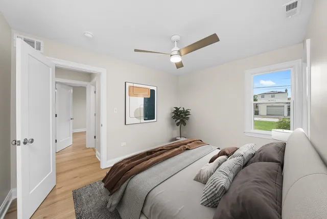 a bedroom with a large bed and a chandelier fan