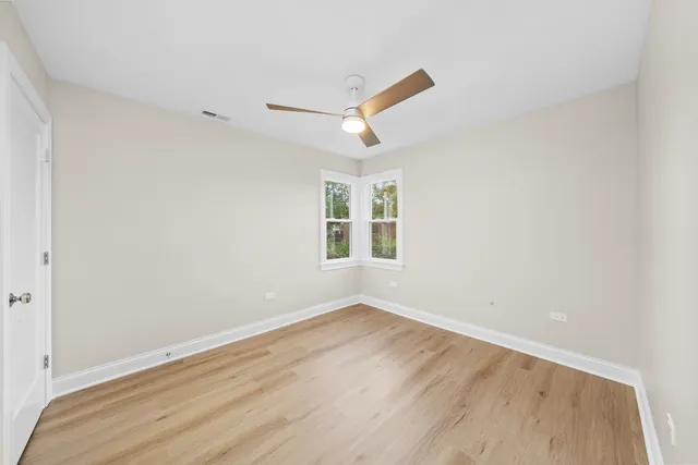 a view of empty room with wooden floor and fan