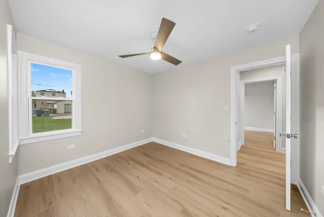an empty room with wooden floor cabinet and windows