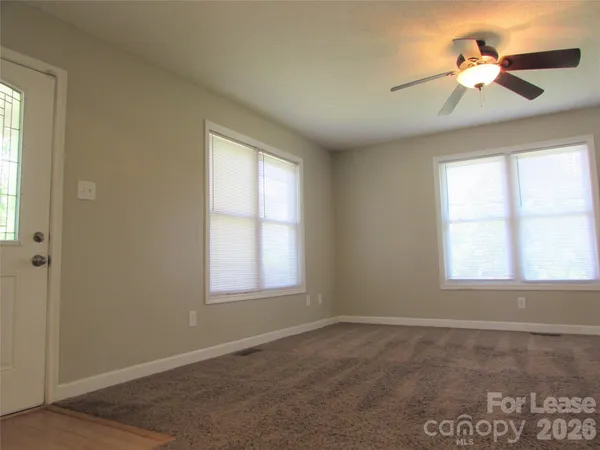 an empty room with windows and fan