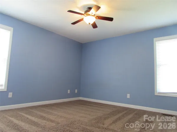 an empty room with a window and a fan
