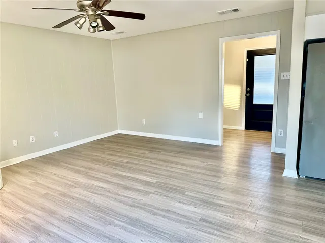 a view of empty room with wooden floor and fan