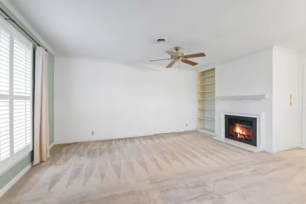 a view of a livingroom with a fireplace a ceiling fan and a chandelier