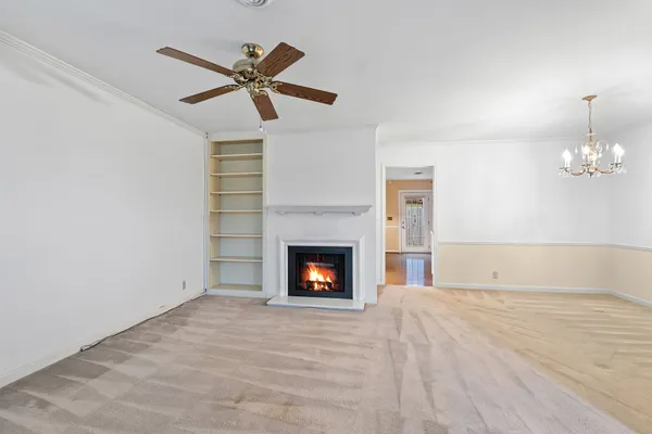 a view of an empty room with chandelier fan and a window