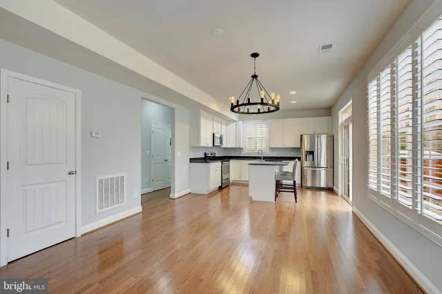 a view of a room with wooden floor chandelier entryway and windows