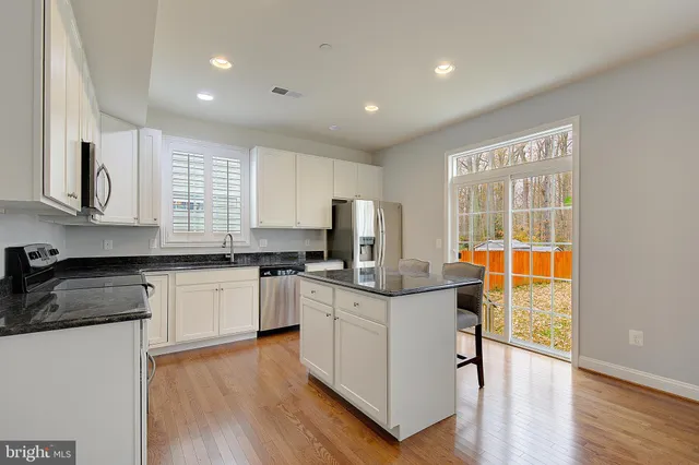 a kitchen with stainless steel appliances granite countertop white cabinets a stove top oven with wooden floor