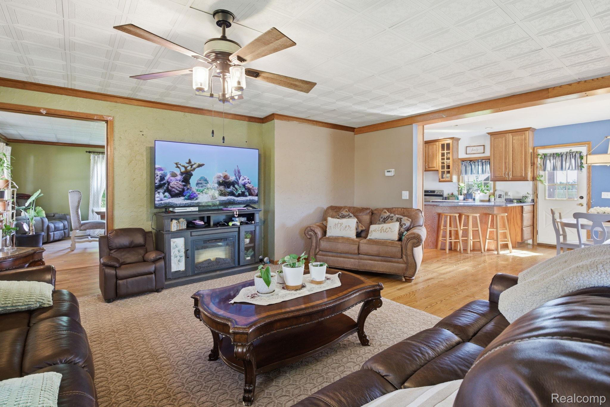 14104 Carleton West Road Carleton, MI 48117 - Photo 9 of 58 Living area featuring a ceiling fan, an ornate ceiling, and light wood-style floors
