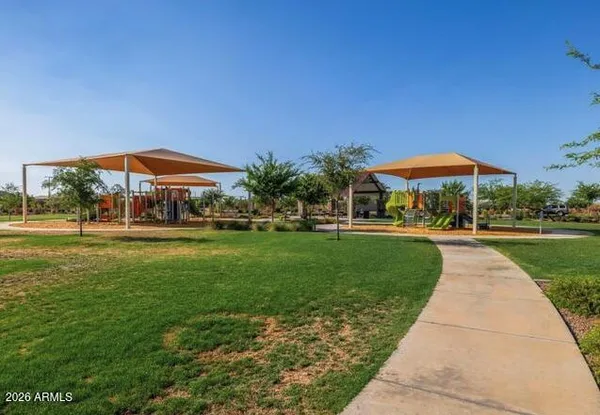 a view of a park with a lawn chairs under an umbrella