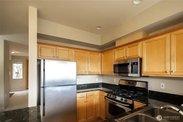 a kitchen with a refrigerator a microwave a sink and cabinets