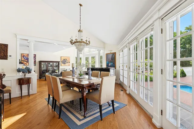 a dining room with wooden floor a chandelier a wooden table and chairs
