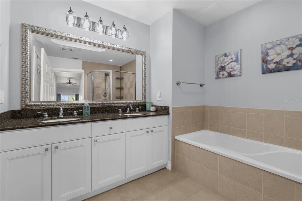 7618 Sandy Ridge Drive, Unit 103 Reunion, FL 34747 - Photo 12 of 37 a bathroom with a bathtub a double vanity sink and a mirror