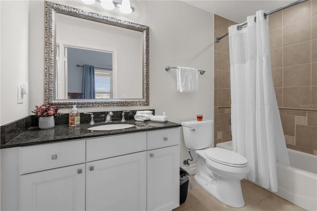 7618 Sandy Ridge Drive, Unit 103 Reunion, FL 34747 - Photo 17 of 37 a bathroom with a granite countertop sink mirror vanity and toilet
