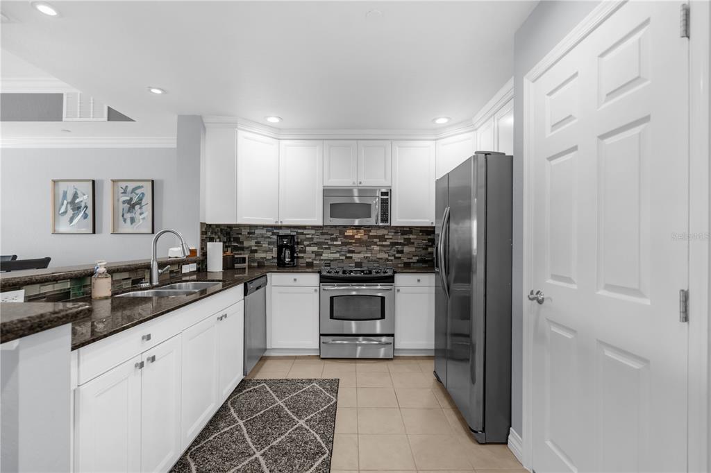 7618 Sandy Ridge Drive, Unit 103 Reunion, FL 34747 - Photo 4 of 37 a kitchen with stainless steel appliances granite countertop a refrigerator and a stove top oven