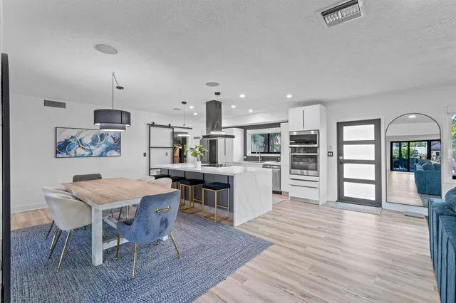 a kitchen with stainless steel appliances kitchen island wooden floors wooden cabinets and dining table