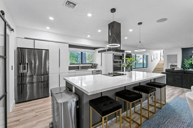 a kitchen with stainless steel appliances kitchen island granite countertop a table chairs and a refrigerator