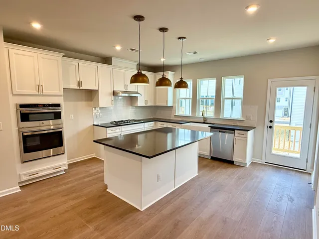 a kitchen with stainless steel appliances granite countertop a sink a stove and a wooden floors