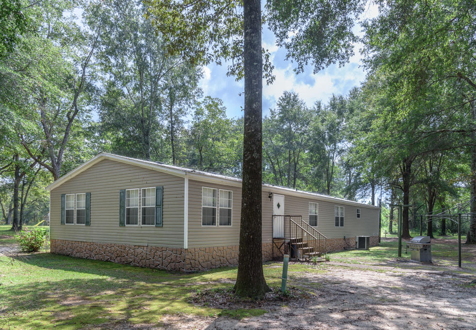 423 Tedder Road East DeFuniak Springs, FL 32433 - Photo 26 of 29 a front view of a house with a garden and trees