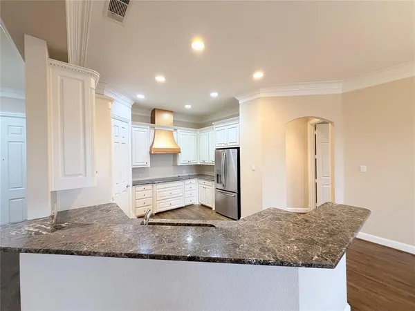 a kitchen with kitchen island granite countertop a sink and a refrigerator