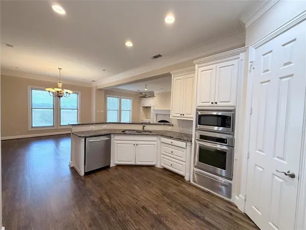 a large kitchen with granite countertop a stove and a wooden floors