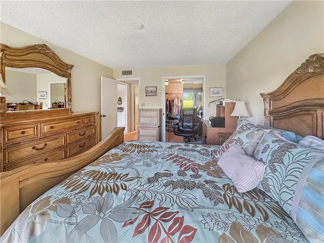 a spacious bedroom with a bed a dresser with mirror