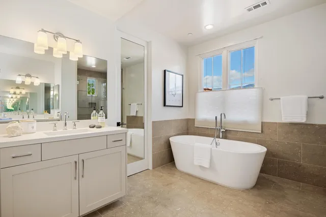 a bathroom with a double vanity sink bathtub and mirror