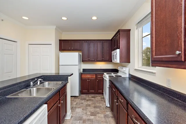 a kitchen with kitchen island granite countertop a sink stove and refrigerator