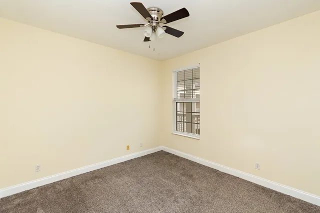 an empty room with windows and fan