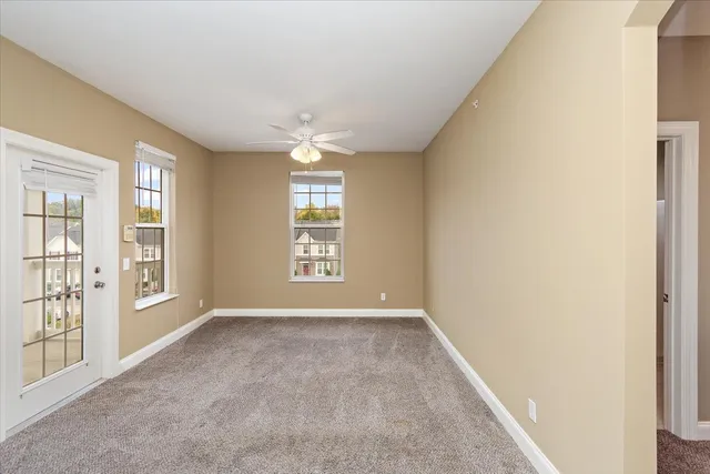 an empty room with windows and chandelier fan