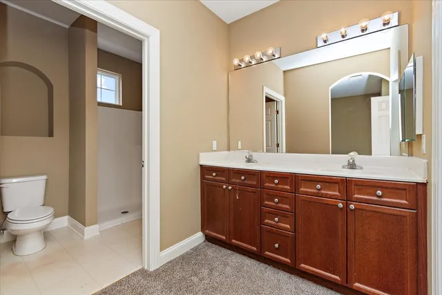 a spacious bathroom with a double vanity sink a toilet and a mirror