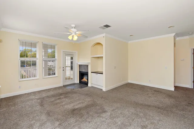 an empty room with chandelier fan and windows