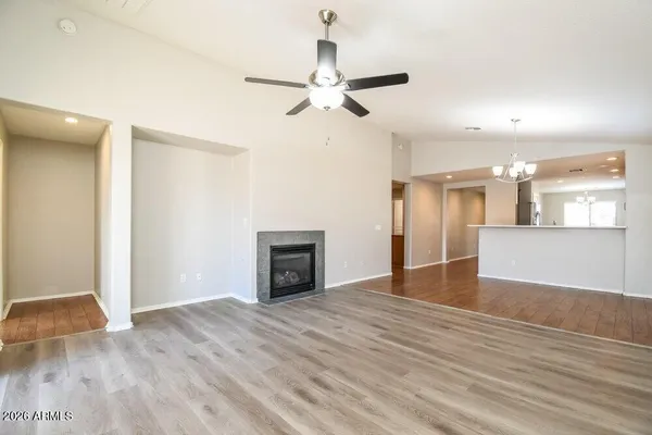 an empty room with wooden floor ceiling fan and windows
