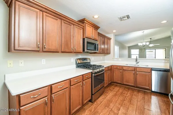 a kitchen with stainless steel appliances granite countertop a stove a sink dishwasher and a microwave oven with wooden floor