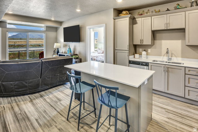 2101 North Main Street, Unit 306 Sunset, UT 84015 - Photo 4 of 22 Open-concept living area featuring a kitchen island with seating, wood-finish flooring, recessed lighting, and a sliding glass door