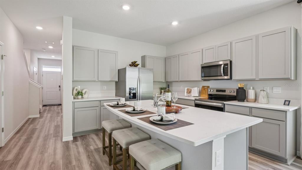 32516 Welling Blade Loop Wesley Chapel, FL 33545 - Photo 12 of 39 a kitchen with a sink a stove a refrigerator and white cabinets with wooden floor