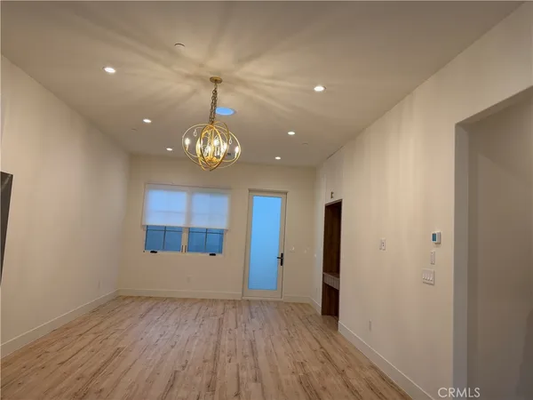 an empty room with wooden floor and chandelier