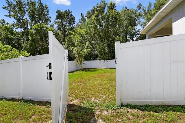 a view of a white house in front of a big yard with large trees