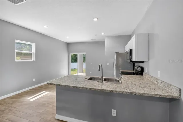a kitchen with stainless steel appliances granite countertop a sink and a refrigerator