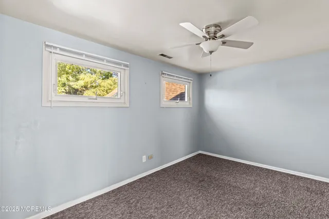 an empty room with a window and a ceiling fan