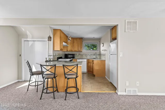 a kitchen with stainless steel appliances kitchen island granite countertop a refrigerator and a stove top oven